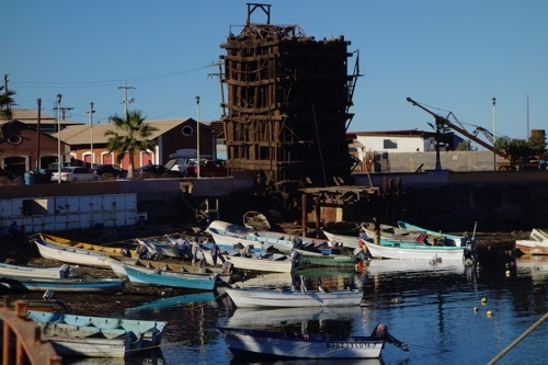 Big wooden tower breaking down slowly at the edge of the harbor