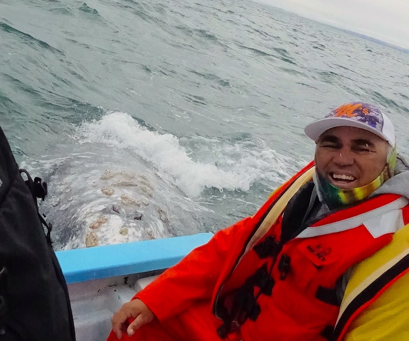 Boat driver grinning as whale approaches boat.
